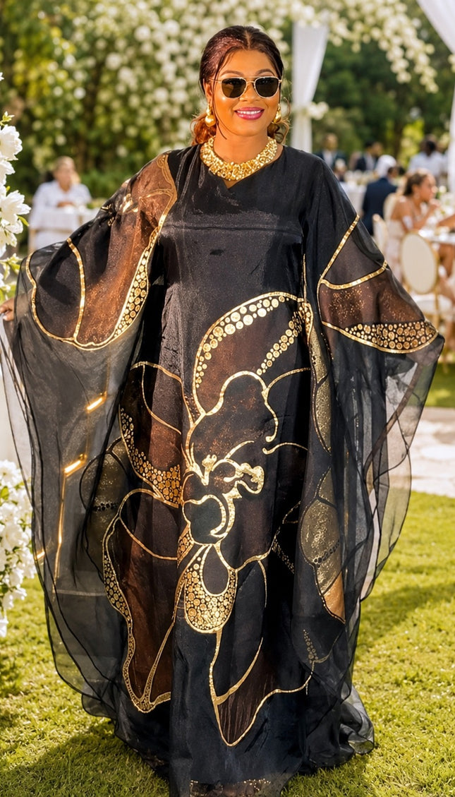 Woman in a black and gold dress at an outdoor event with floral decorations.