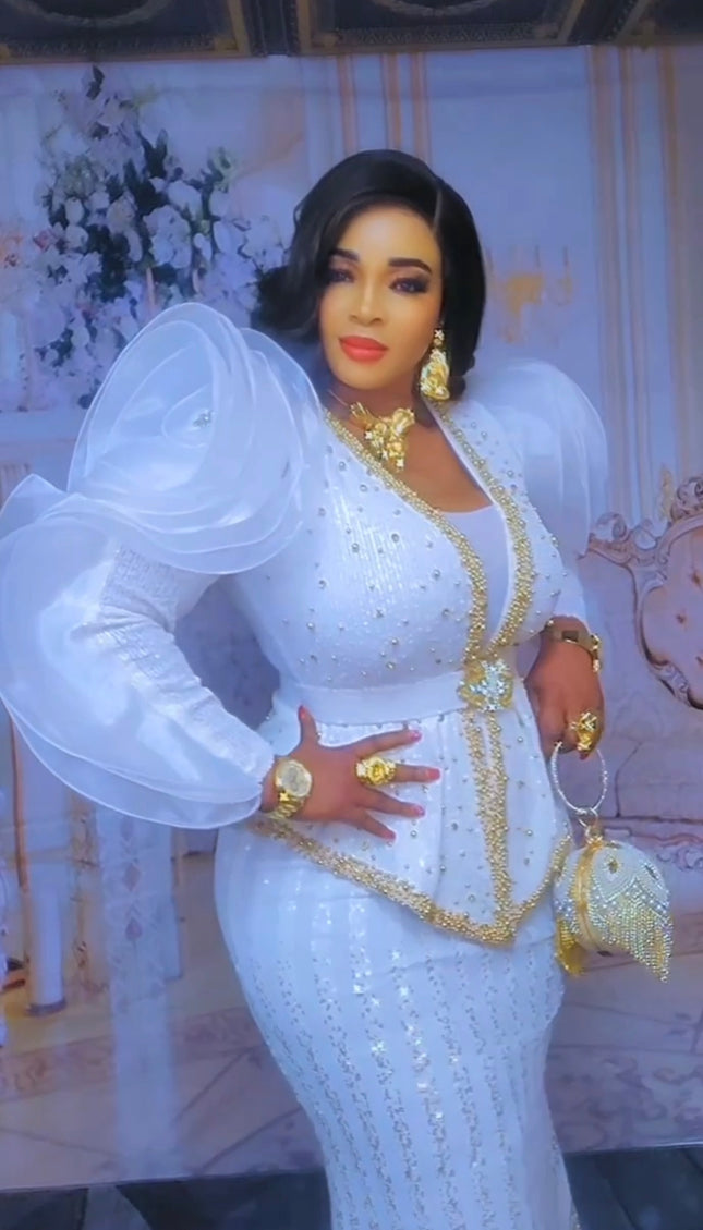 Woman in a white and gold dress posing in front of a decorative background