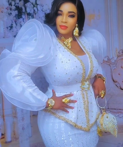 Woman in a white and gold dress posing in front of a decorative background